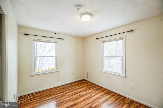 empty room featuring baseboards, light wood-style flooring, and a textured ceiling