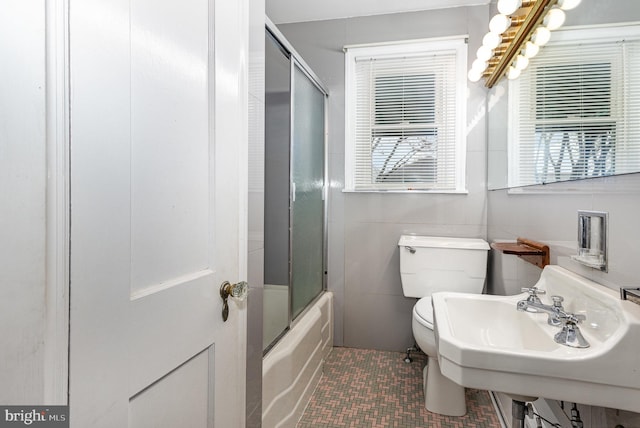 bathroom with bath / shower combo with glass door, toilet, tile patterned flooring, and a sink