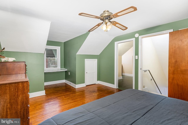 bedroom featuring lofted ceiling, baseboards, wood finished floors, and ceiling fan