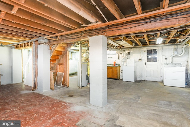below grade area featuring electric water heater, heating fuel, and washer / clothes dryer