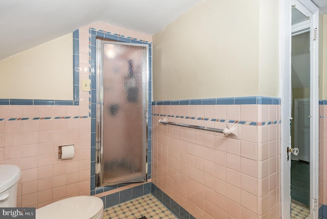full bath with a shower stall, tile patterned flooring, a wainscoted wall, toilet, and tile walls