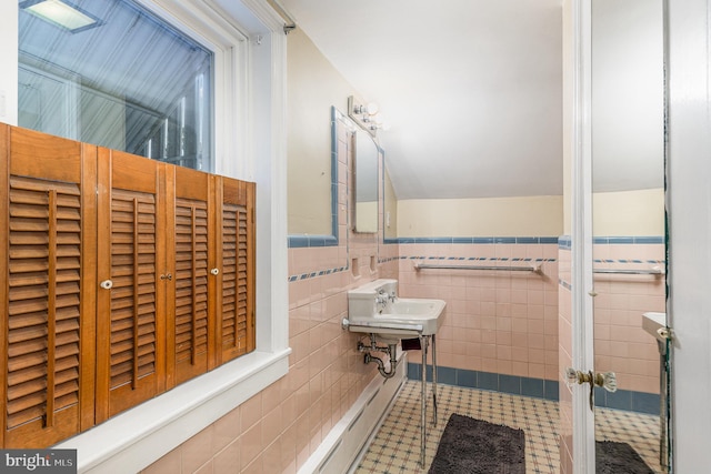 bathroom with tile walls, tile patterned floors, a wainscoted wall, and a sink