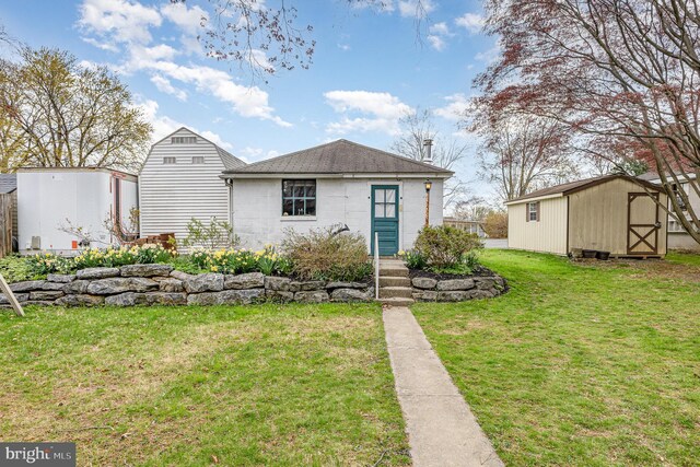 view of front of house featuring a front lawn, roof with shingles, an outdoor structure, and a storage unit