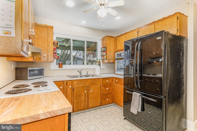 kitchen featuring oven, stainless steel microwave, black fridge, white electric cooktop, and under cabinet range hood