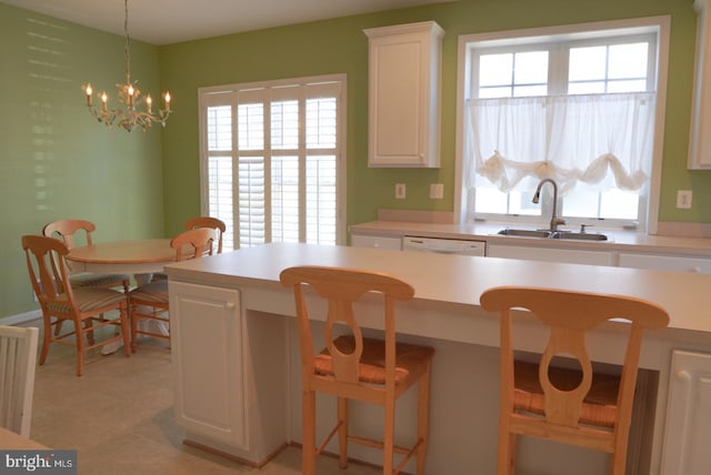 kitchen featuring light countertops, hanging light fixtures, white cabinetry, a sink, and a kitchen bar