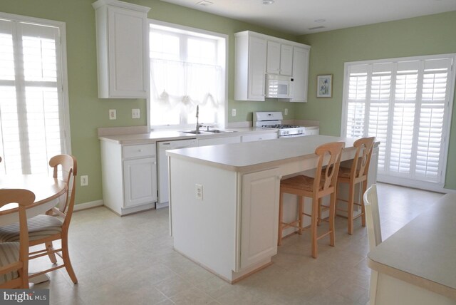 kitchen featuring white appliances, light countertops, a sink, and white cabinets