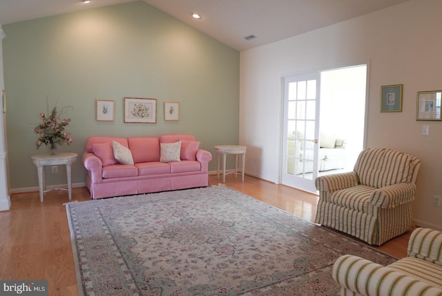 living room featuring lofted ceiling, recessed lighting, visible vents, baseboards, and light wood-type flooring