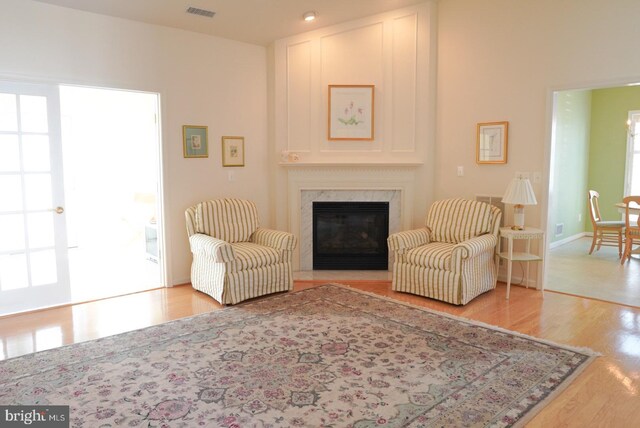 living area with visible vents, a premium fireplace, plenty of natural light, and light wood-style flooring