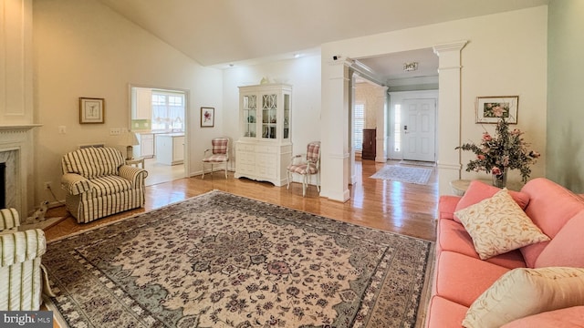 living room featuring decorative columns, baseboards, lofted ceiling, a premium fireplace, and wood finished floors