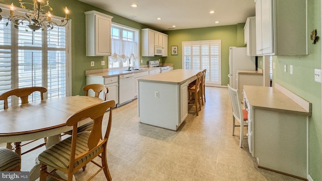 kitchen featuring recessed lighting, white appliances, a kitchen island, white cabinets, and light countertops