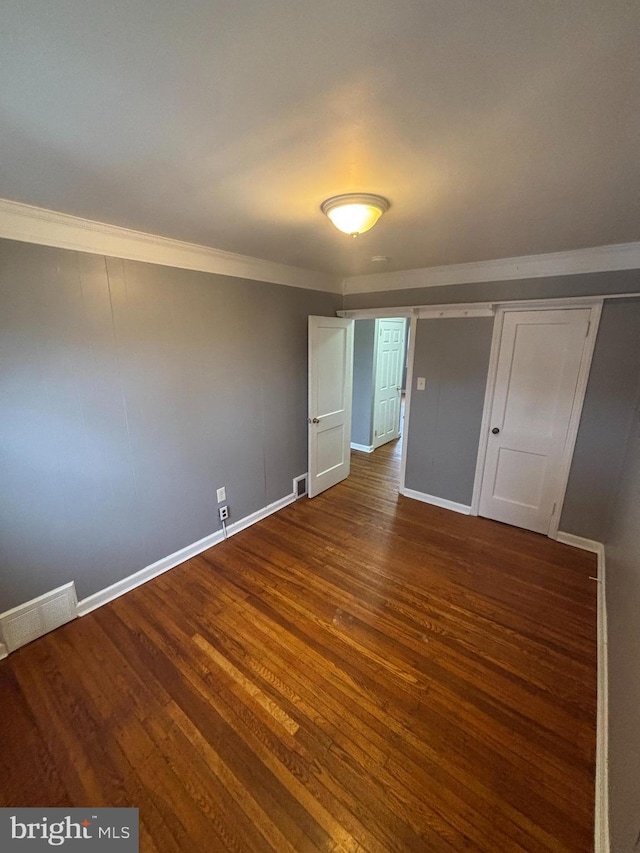 unfurnished bedroom featuring crown molding, dark hardwood / wood-style floors, and a closet