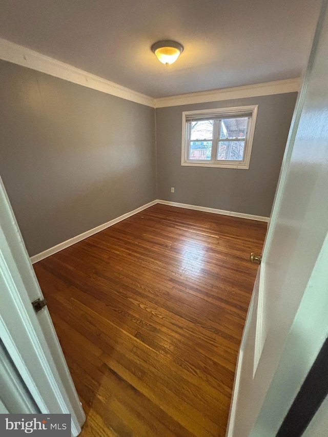 empty room with ornamental molding and dark wood-type flooring