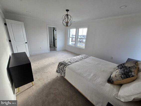 carpeted bedroom featuring crown molding and a chandelier