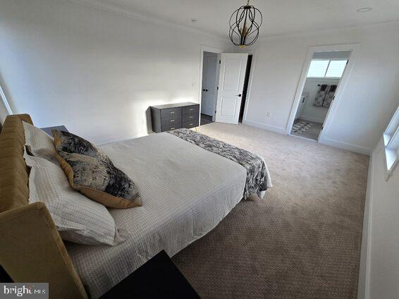 bedroom with an inviting chandelier, ornamental molding, and carpet flooring