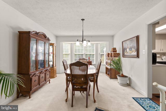 carpeted dining space with a textured ceiling and a chandelier