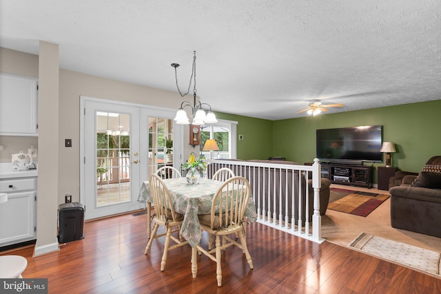 dining space with a chandelier, hardwood / wood-style floors, a textured ceiling, and french doors