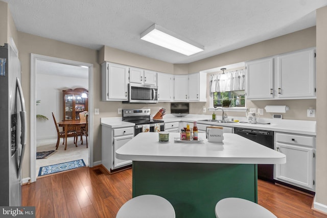 kitchen with white cabinetry, sink, stainless steel appliances, and a center island