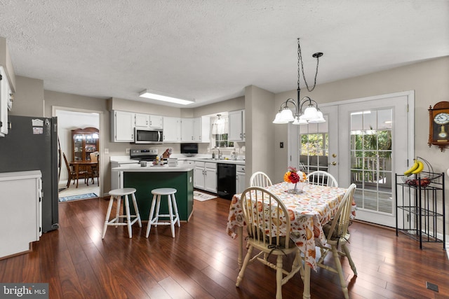 dining space with an inviting chandelier, dark hardwood / wood-style floors, sink, and a textured ceiling