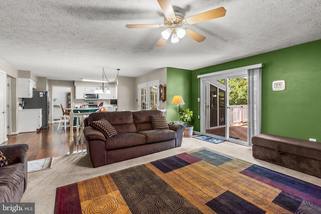 carpeted living room with a textured ceiling and ceiling fan