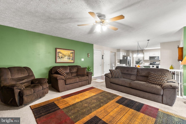 living room featuring ceiling fan, light colored carpet, and a textured ceiling