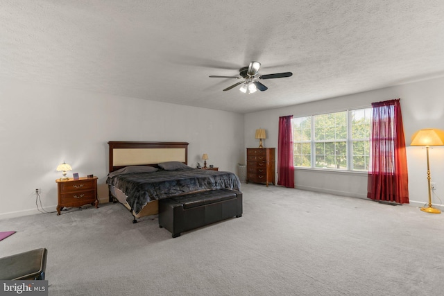 bedroom with ceiling fan, light colored carpet, and a textured ceiling