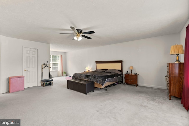 bedroom featuring light colored carpet, a textured ceiling, and ceiling fan