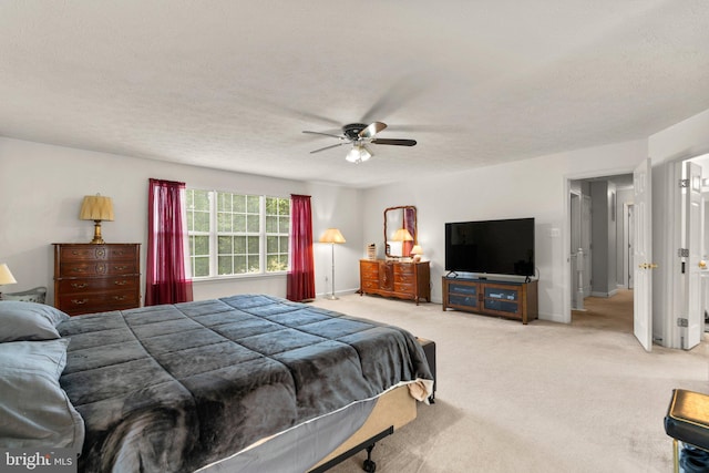 bedroom featuring ceiling fan, light colored carpet, and a textured ceiling