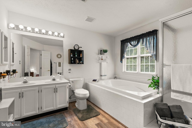 full bathroom with toilet, a textured ceiling, vanity, independent shower and bath, and hardwood / wood-style flooring