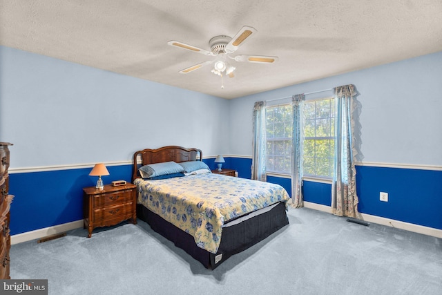 bedroom featuring ceiling fan, light colored carpet, and a textured ceiling