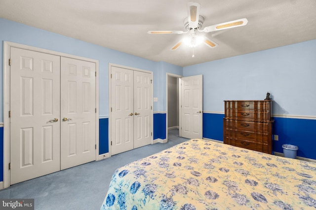 bedroom featuring light carpet, two closets, and ceiling fan