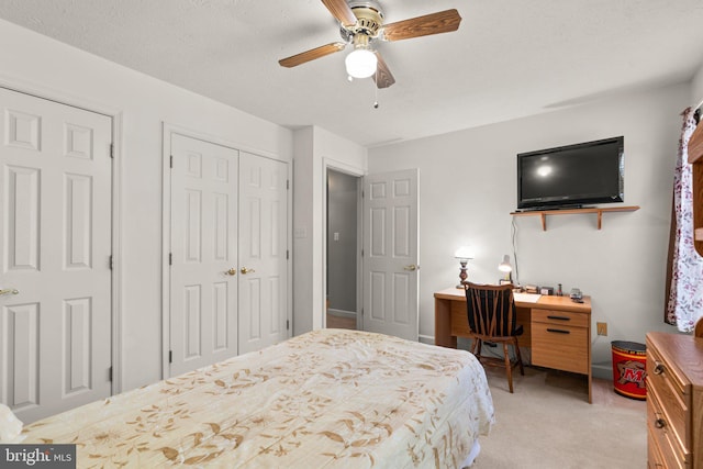 bedroom with ceiling fan, light carpet, a textured ceiling, and a closet