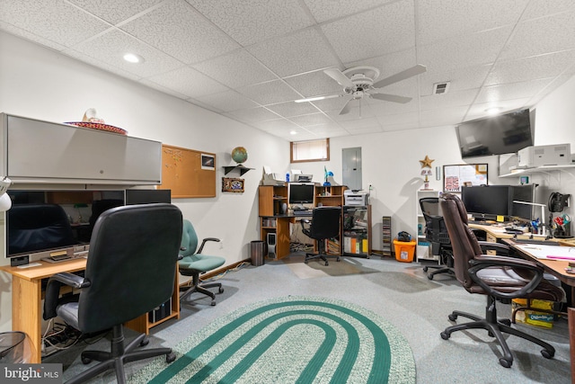 carpeted office featuring a drop ceiling, ceiling fan, and electric panel