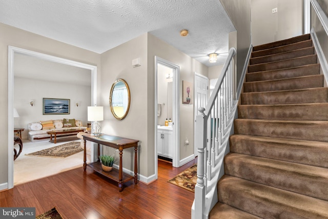 staircase featuring hardwood / wood-style floors and a textured ceiling