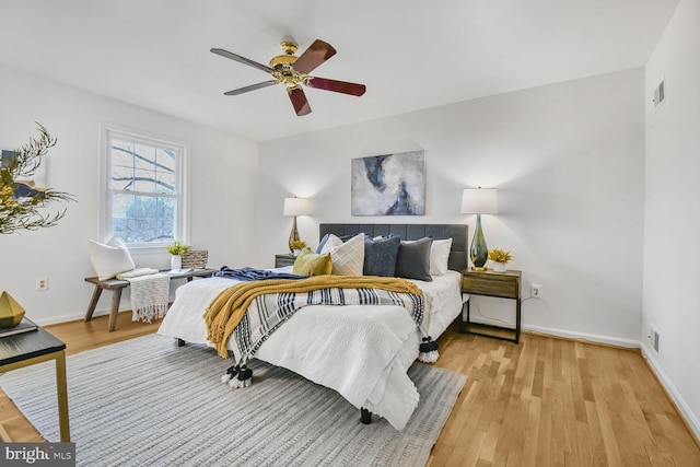 bedroom with ceiling fan, visible vents, light wood-type flooring, and baseboards