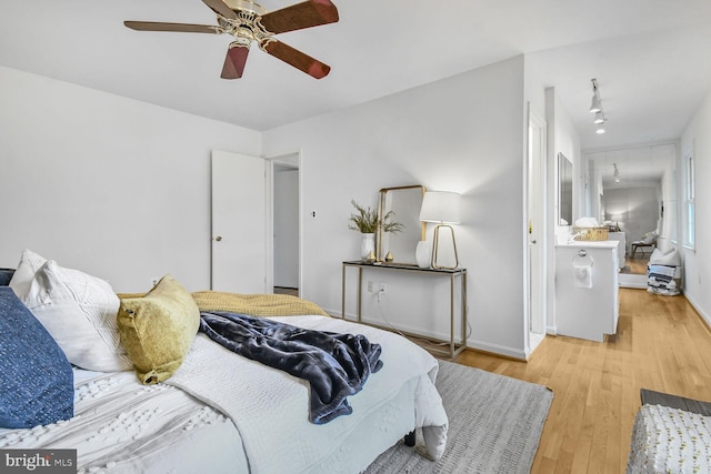 bedroom featuring ceiling fan, rail lighting, light wood-type flooring, and baseboards