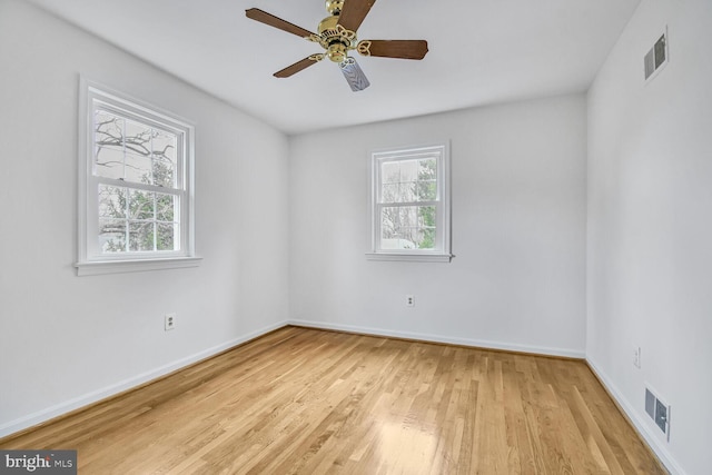 spare room featuring plenty of natural light, light wood-style floors, visible vents, and baseboards