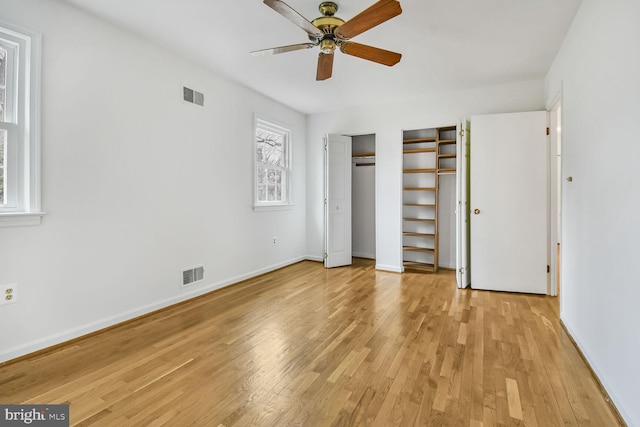 unfurnished bedroom with light wood finished floors, visible vents, baseboards, and multiple closets