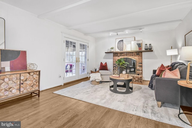 living area featuring wood finished floors, beamed ceiling, baseboards, french doors, and a brick fireplace