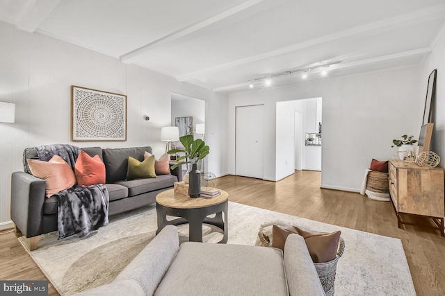 living area featuring beamed ceiling, baseboards, and wood finished floors