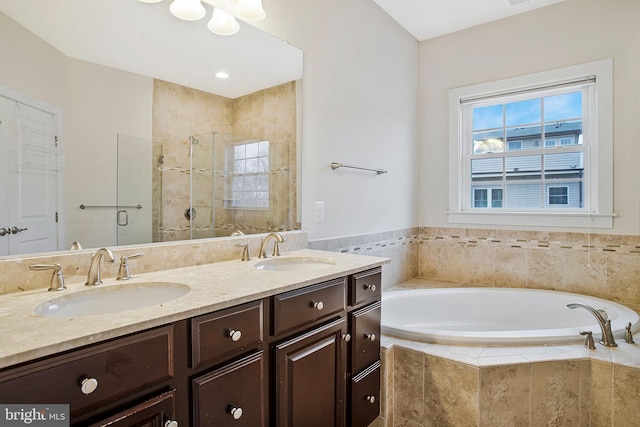 bathroom with double vanity, a stall shower, a garden tub, and a sink