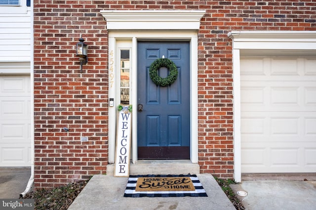 entrance to property with a garage and brick siding