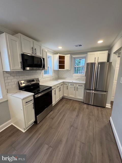 kitchen with tasteful backsplash, white cabinetry, appliances with stainless steel finishes, and dark hardwood / wood-style floors