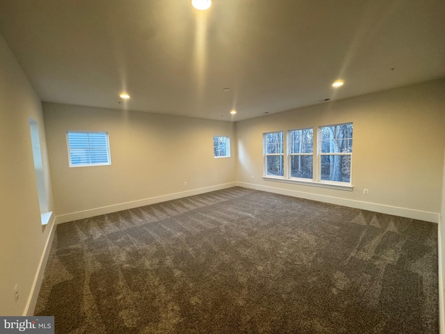 empty room featuring baseboards, dark colored carpet, a wealth of natural light, and recessed lighting