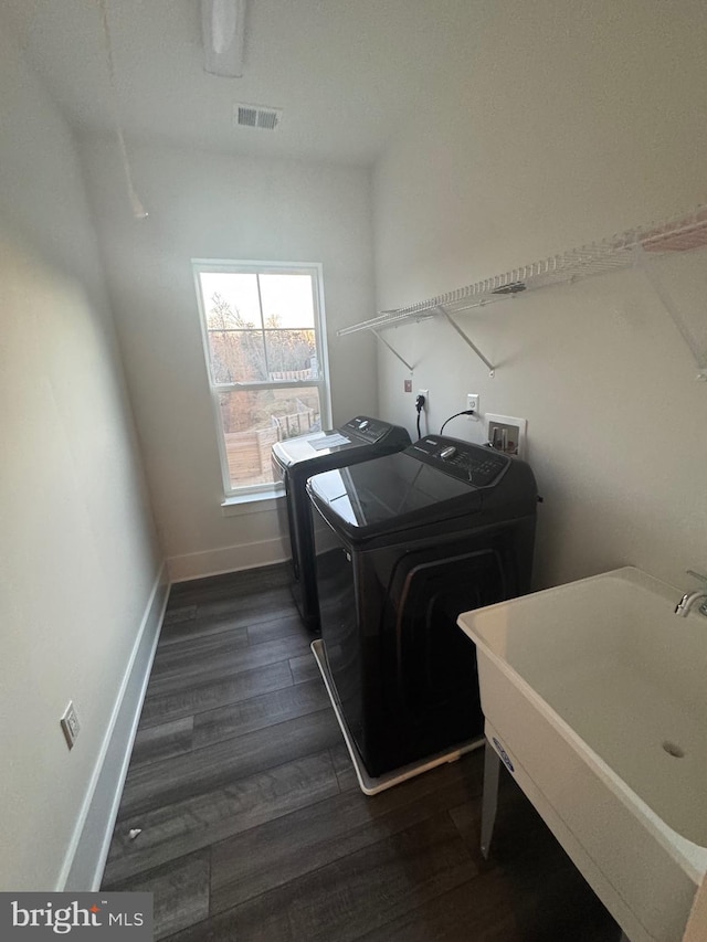 clothes washing area with laundry area, visible vents, dark wood finished floors, washing machine and dryer, and a sink