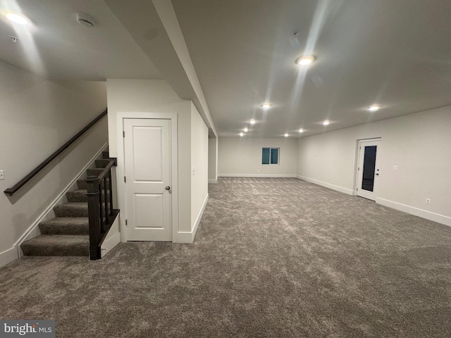 finished basement with dark colored carpet, stairway, and baseboards