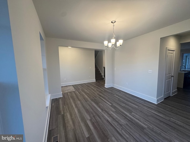 empty room with visible vents, baseboards, stairway, dark wood-type flooring, and a notable chandelier