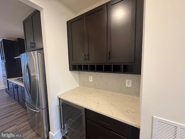 kitchen featuring dark brown cabinetry, tasteful backsplash, dark wood-style floors, wine cooler, and freestanding refrigerator