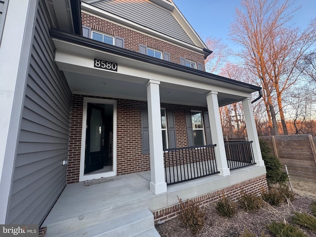 property entrance featuring covered porch and brick siding