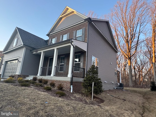 view of front facade with a porch, crawl space, an attached garage, and central air condition unit