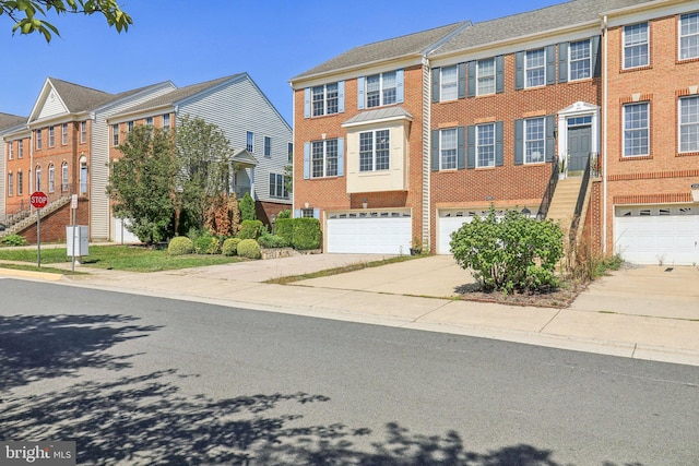 townhome / multi-family property featuring driveway, a garage, a residential view, and brick siding